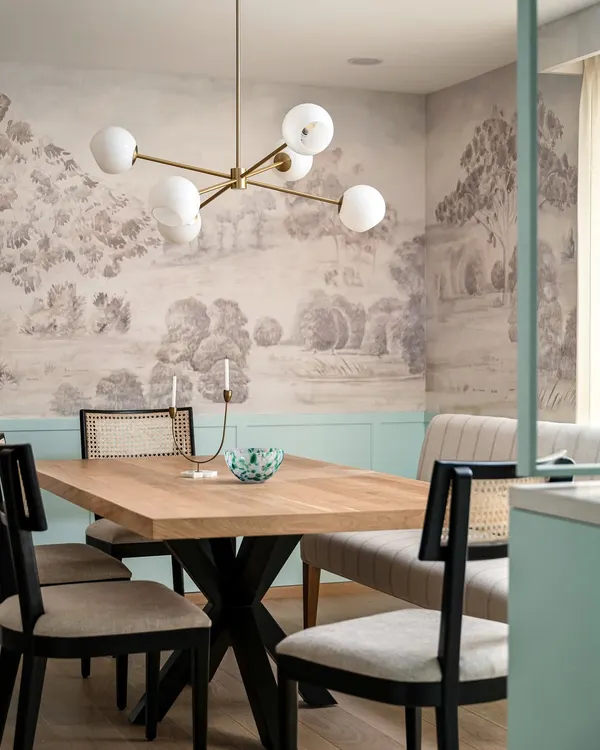 This dining space from the Aqua Home features a stunning custom mural and duck egg blue wainscoting. The mix of a bench and cane-back chairs creates a relaxed yet sophisticated atmosphere, perfect for family meals.