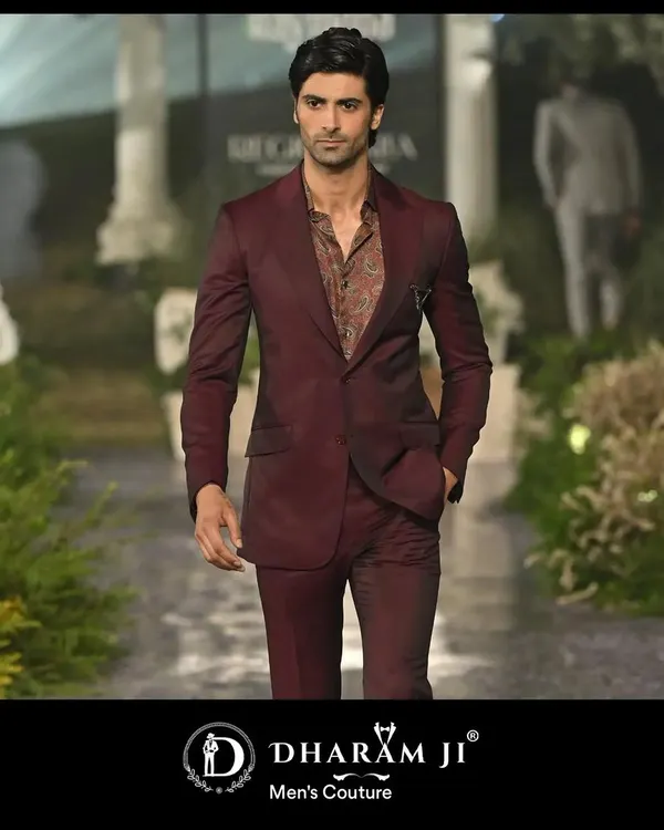 A model on the runway in a deep maroon suit. The slim fit and rich color make it a sophisticated choice for a wedding reception or formal dinner.
