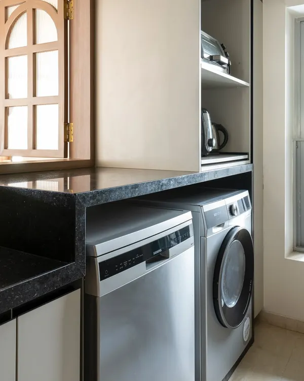 Integrating laundry into the kitchen is a smart solution for modern Indian homes. Here, the dishwasher and washing machine sit side-by-side under the counter, making the kitchen a highly efficient hub for all household chores.