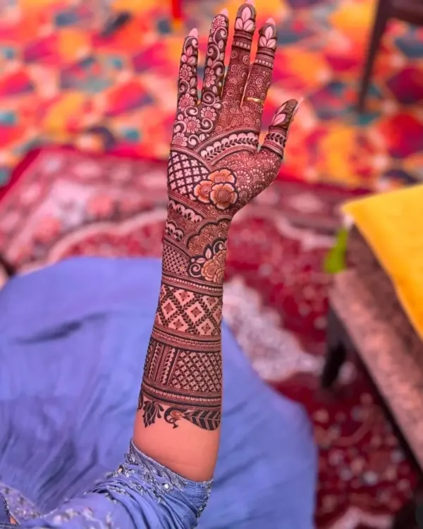 A beautiful example of engagement mehndi, with a focus on floral patterns and a delicate net design on the back of the hand.
