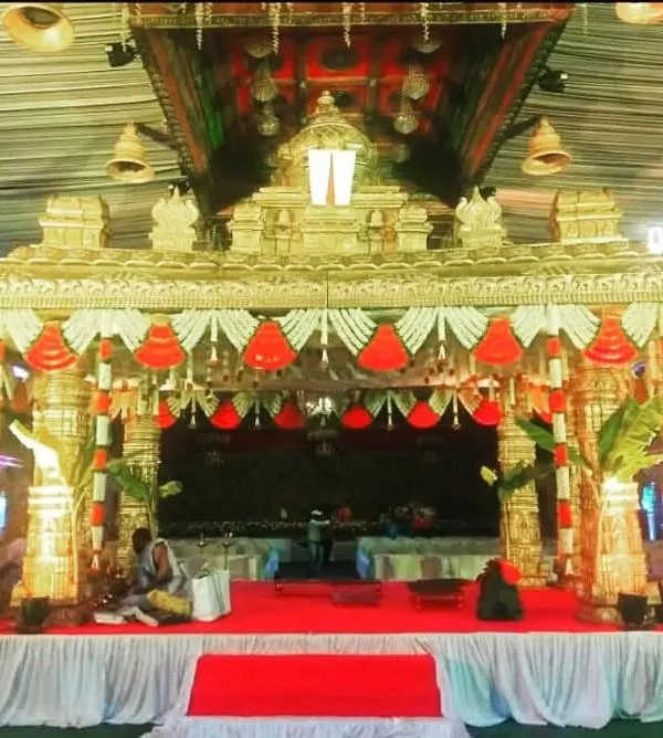 This 'Tirupati' style mandap is designed to replicate the grandeur of a temple, with ornate pillars, a detailed roof structure, and traditional bell hangings for an authentic ceremonial feel.