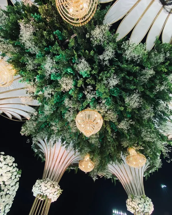 This is a view looking up at a ceiling installation I created. It features a dense base of fresh greenery mixed with baby's breath, with elegant crystal chandeliers hanging down to create a magical, forest-like canopy.
