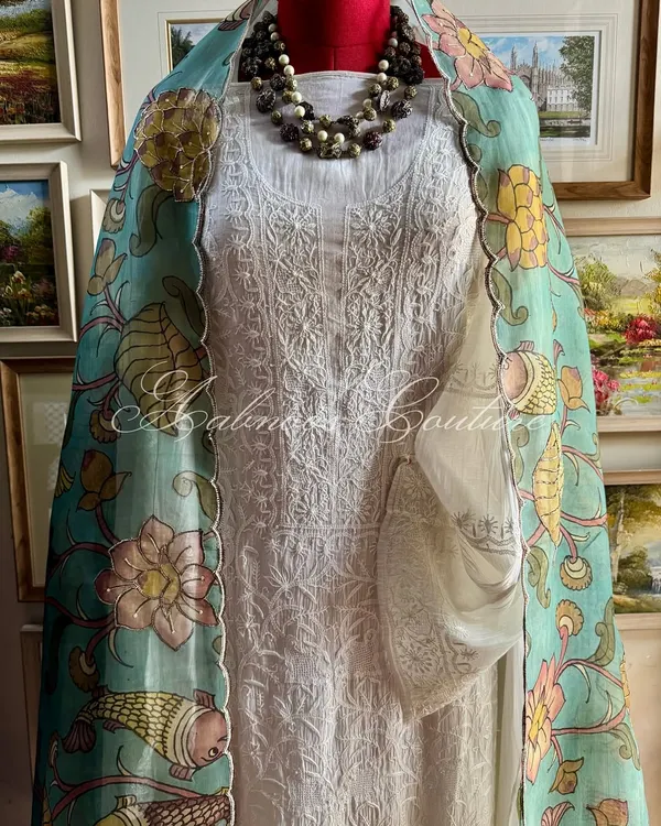We present a complete ensemble that embodies understated luxury. This look pairs an exquisite off-white hand-embroidered Chikankari suit with our hand-painted Srikalahasti Kalamkari organza dupatta, creating a harmonious blend of two revered Indian crafts.