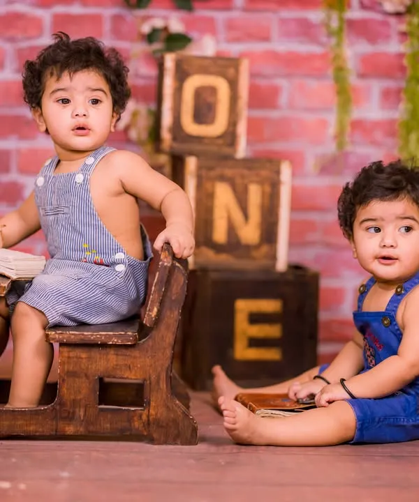 Our rustic schoolhouse set is a fantastic choice for twins. It's spacious enough for two and comes with props like a mini school desk, chalkboard, and "ONE" blocks for a charming first birthday shoot.