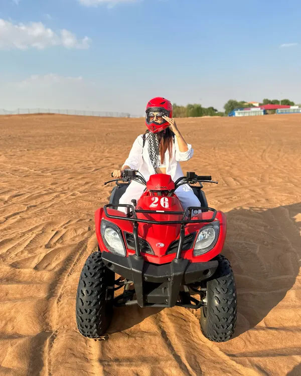 Kicking off my desert adventure in Abu Dhabi with some quad biking. I'm wearing a comfortable all-white outfit with a keffiyeh scarf for a practical and stylish desert look.