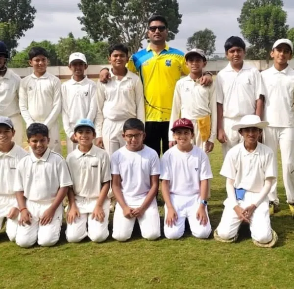 Our young team with their coach, ready for a match on a well-maintained grass field.