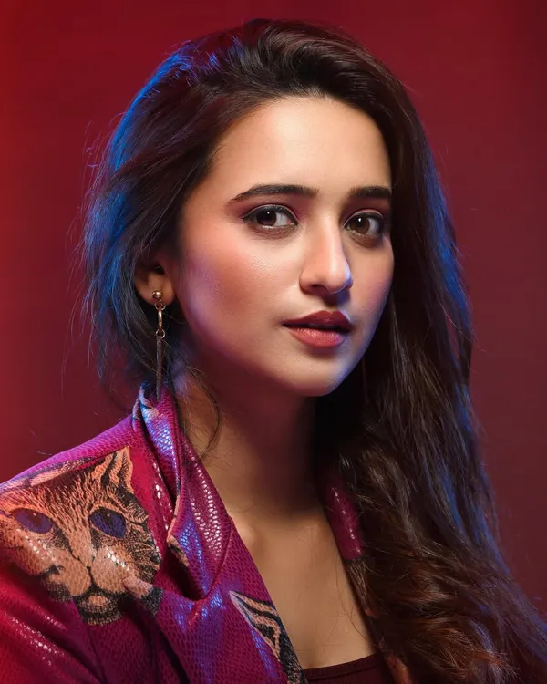 This portrait combines fashion with a cinematic mood. The red background and subtle blue highlights create a vibrant color palette, while the model's direct gaze makes for a confident and engaging shot, perfect for an actor's lookbook.