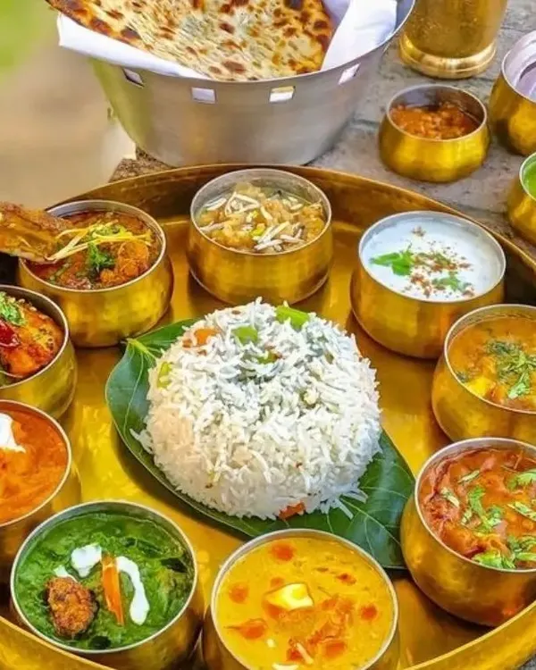 A glimpse into our grand vegetarian thali, a complete meal featuring an assortment of our finest curries, dal, rice, bread, and dessert, served in traditional brass bowls.