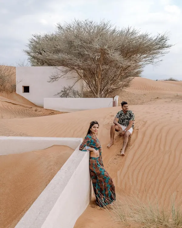 A destination pre-wedding shoot in the stunning Dubai desert. The unique architecture half-buried in sand creates a surreal and beautiful setting for this couple's portrait, showcasing how exotic locations can elevate a photoshoot.