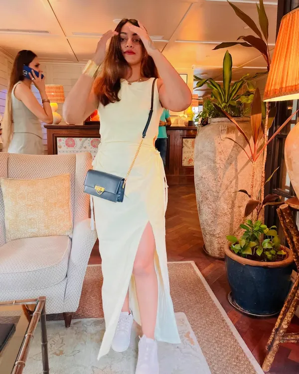A full-length shot of this pale yellow dress with a side slit, paired with white sneakers for a casual, comfortable vibe. This is a great example of how to style a dress for a relaxed day out.
