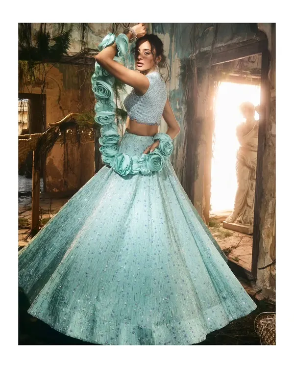 This dramatic lehenga in a serene aqua tone is a perfect example of modern couture. The sculptural floral details and voluminous, shimmering skirt create a silhouette that is both unforgettable and moves with a beautiful lightness, ideal for a contemporary bride or a grand reception.