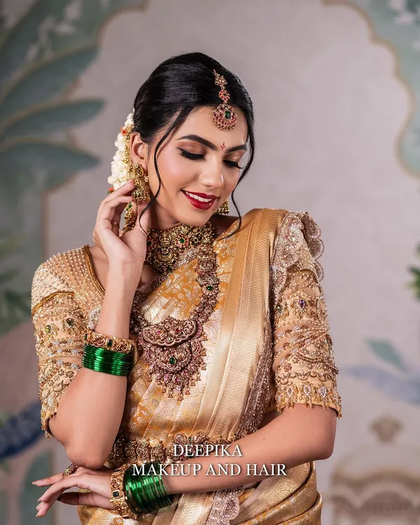 A close-up of a radiant South Indian bride. Notice the soft, shimmering eye makeup and the perfectly blended base that enhances her natural beauty, paired with a classic red lip.