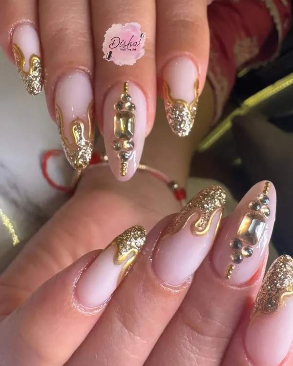 A close-up of our special Karwachauth nails. This design features a neutral base with dripping gold glitter, 3D gold accents, and large gemstone embellishments for a truly festive look.