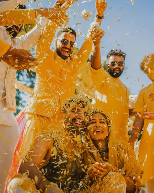 The grand finale of a fun-filled Haldi, with the couple and their friends celebrating amidst a shower of flower petals. This is pure, unfiltered joy.