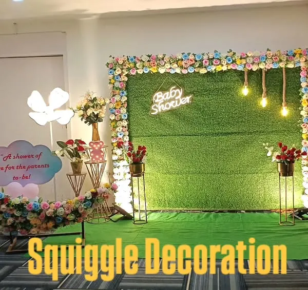 A unique and modern baby shower setup. This design features a floral crescent moon prop, a 'Baby Shower' sign, and character cutouts on an artificial grass backdrop.