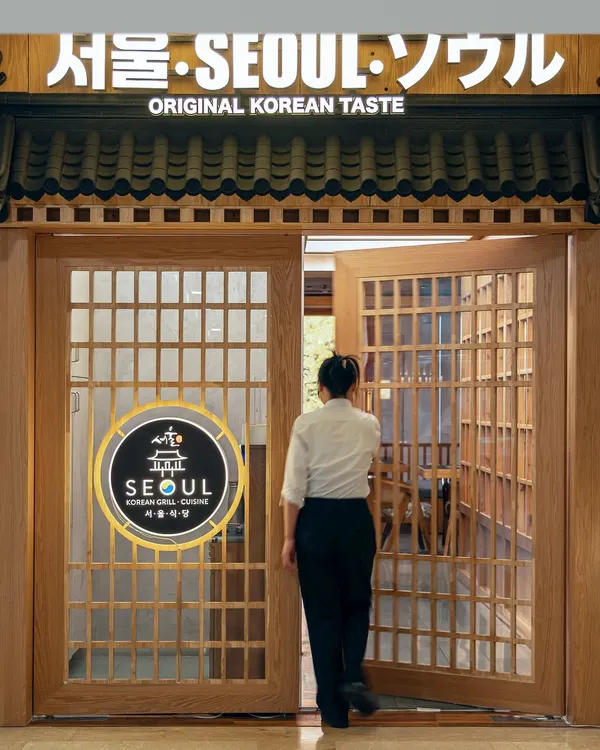 The entrance to Seoul was designed to be a cultural gateway. The traditional wooden lattice doors and signage in multiple scripts immediately signal a space dedicated to authentic Korean taste, setting a narrative tone from the very first step.