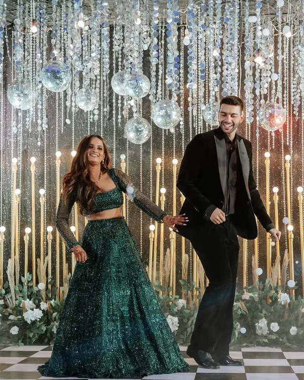 A sangeet night designed for glamour and fun. The couple dances on a checkered floor under a ceiling of hanging disco balls and crystal strings, creating a dazzling, high-energy atmosphere perfect for celebrating.