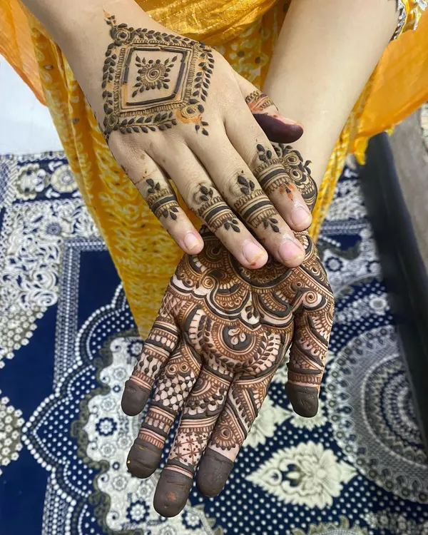 A beautiful combination of two different styles on each hand, one with a geometric pattern and the other with a more traditional, full-palm design.