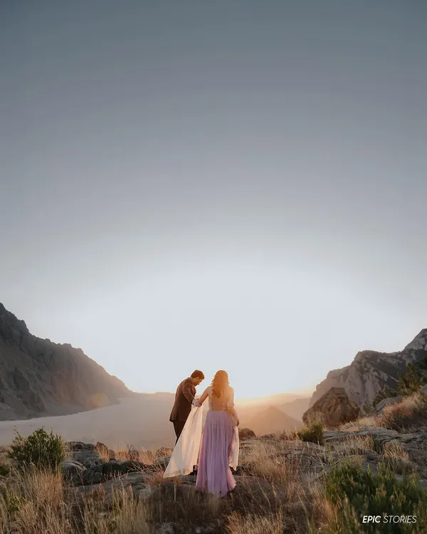 A breathtaking sunset shoot in the mountains. This image is all about the scale of nature and the intimacy of the couple within it. The groom helping his partner with her dress is a small, beautiful gesture of love.