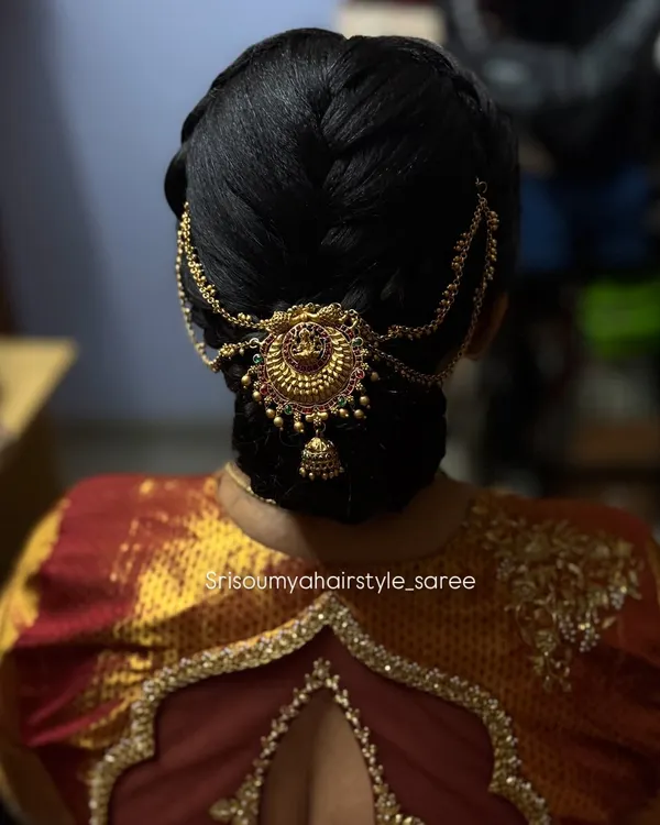 A close-up of this elegant traditional updo. The bun is adorned with a beautiful piece of temple jewelry, perfect for a classic South Indian look.