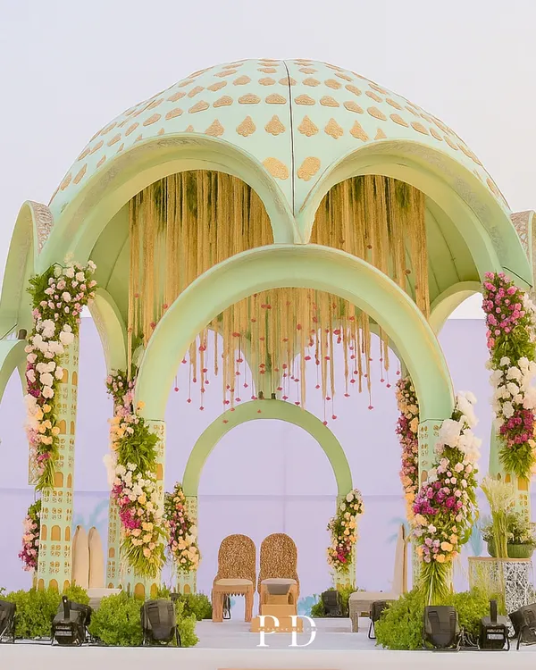 A close-up of our Sheesh Mahal-inspired mandap, showcasing the pastel green dome with intricate gold-leaf patterns. This structure was designed to feel grand yet delicate, creating a fairytale setting for the vows.