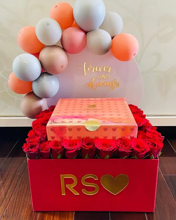 A truly romantic gesture for your forever and always. This custom red box is filled with dozens of fresh roses and topped with a personalized balloon arch and a box of luxury sweets.