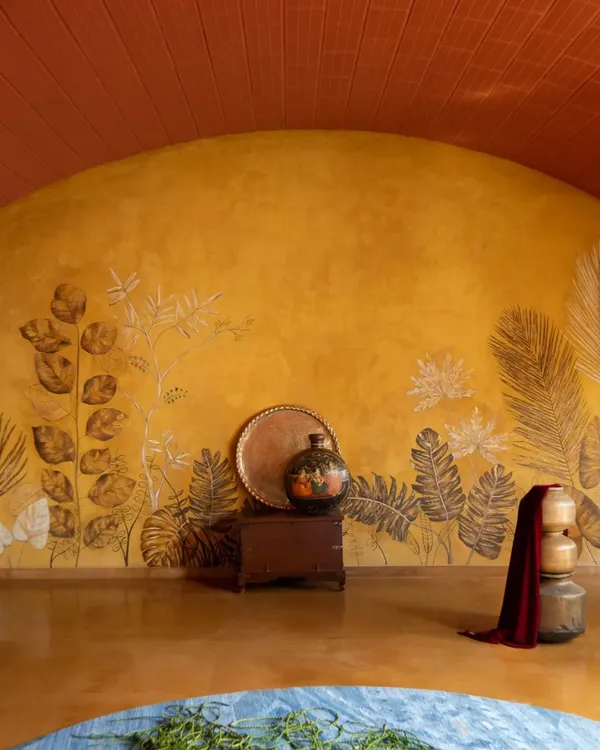 This curved feature wall is finished in yellow oxide with leaf imprints, created in collaboration with an artist. The wall becomes a canvas, bringing the texture and patterns of the outdoor landscape into the living space.