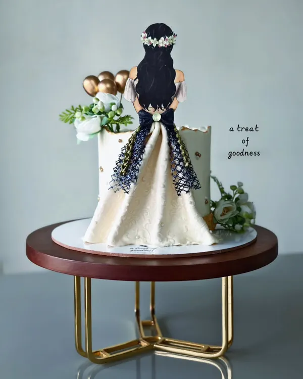 A chic and elegant cake for a bride-to-be. The design features a hand-piped dress illustration on a simple white buttercream cake, creating a beautiful and personal statement piece.