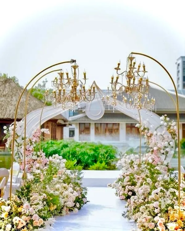 An absolutely enchanting wedding entrance. We designed this walkway with golden arches holding magnificent chandeliers, surrounded by a garden of pastel pink and white flowers.