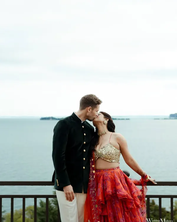 A kiss overlooking the serene waters of Lake Garda, Italy. Nimisha and Benzamin's vibrant traditional outfits created a beautiful contrast against the calm blue backdrop for their destination wedding shoot.