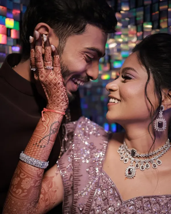 A beautiful, intimate moment between the couple at their sangeet. The bride's makeup is glowing, with a focus on her intricate henna and stunning diamond jewellery.