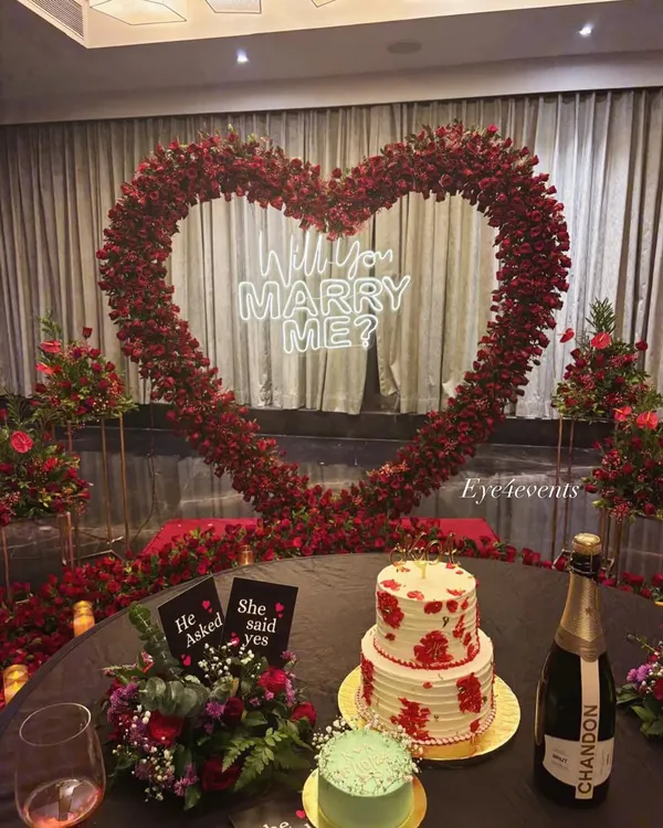 We create the perfect backdrop for life's biggest questions. This stunning proposal setup features a custom heart-shaped arch of red roses and a neon "Will You Marry Me?" sign, setting the stage for a guaranteed yes.