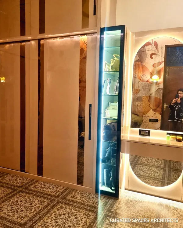 A side view of the custom closet room, showing the seamless integration of the sliding wardrobe and the vanity unit. The vertical lighting on the display cabinet adds a touch of glamour.