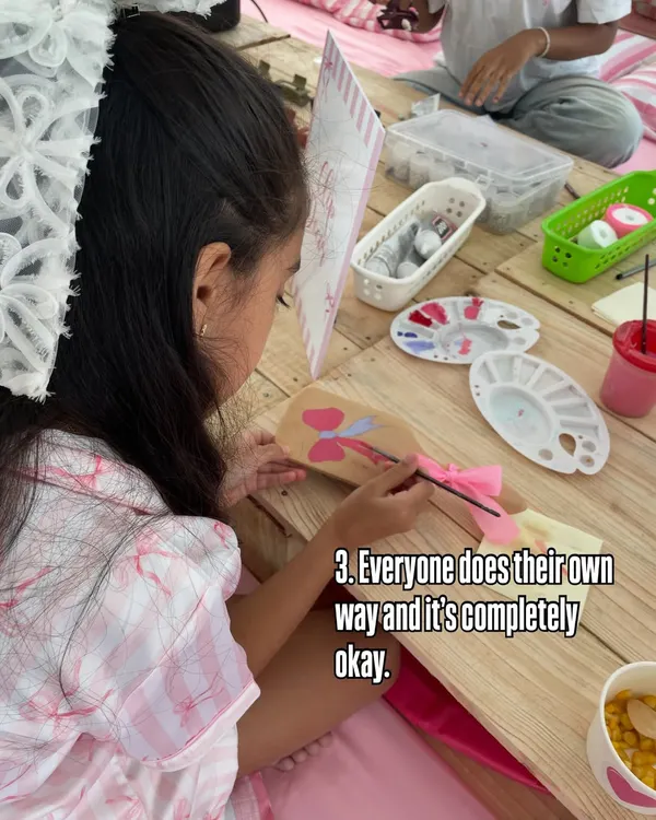 One of the beautiful things I observe is that every child does it their own way, and it's completely okay. This young girl is carefully painting a wooden paddle with her unique design.