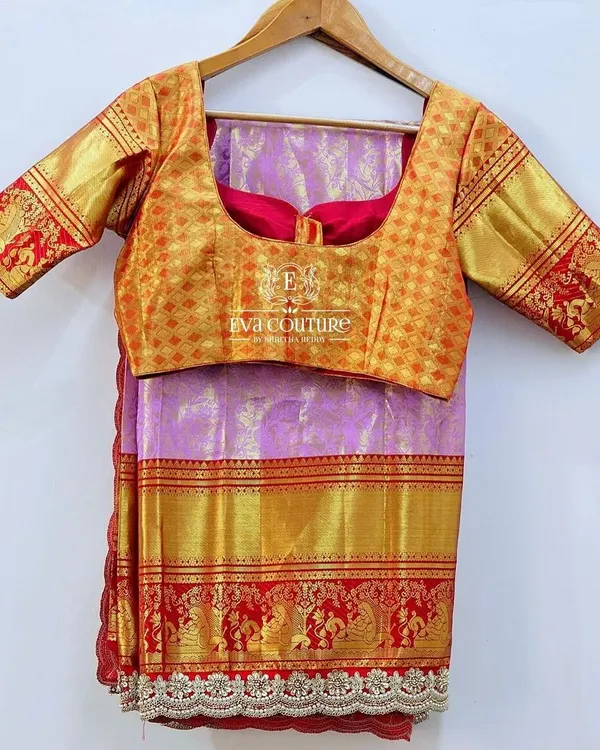 A beautiful Kanchi Pattu saree in lilac with a red and gold border. It is paired with a contrasting gold brocade blouse for a classic and elegant look.