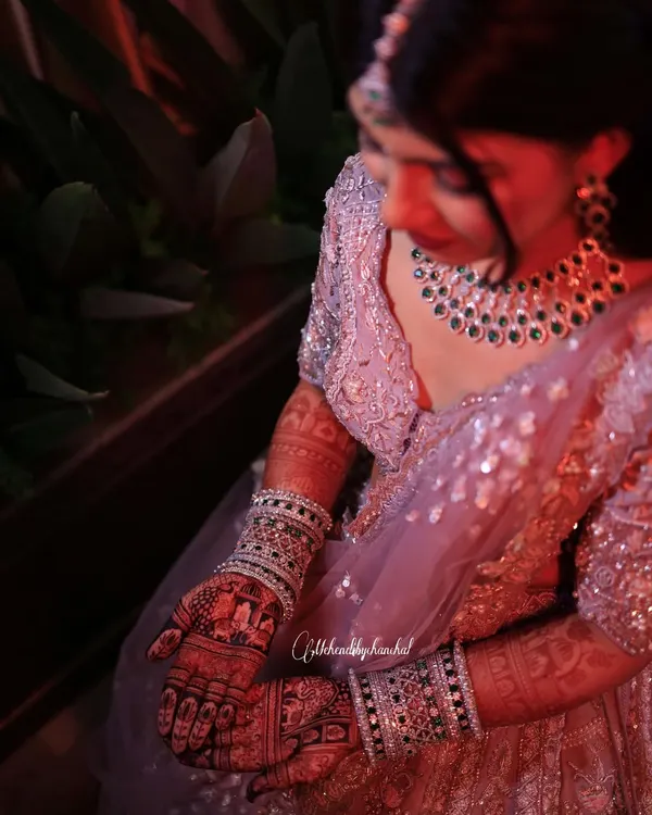 A beautiful bride admiring her dark mehendi stain on her big day. The rich color provides a stunning contrast with her jewelry and outfit.