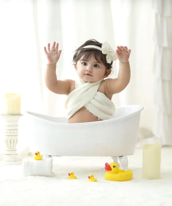 A moment of pure joy as this little one raises her hands during our classic white-themed bathtub session. The minimalist setup with soft lighting puts all the focus on your baby's adorable expression.