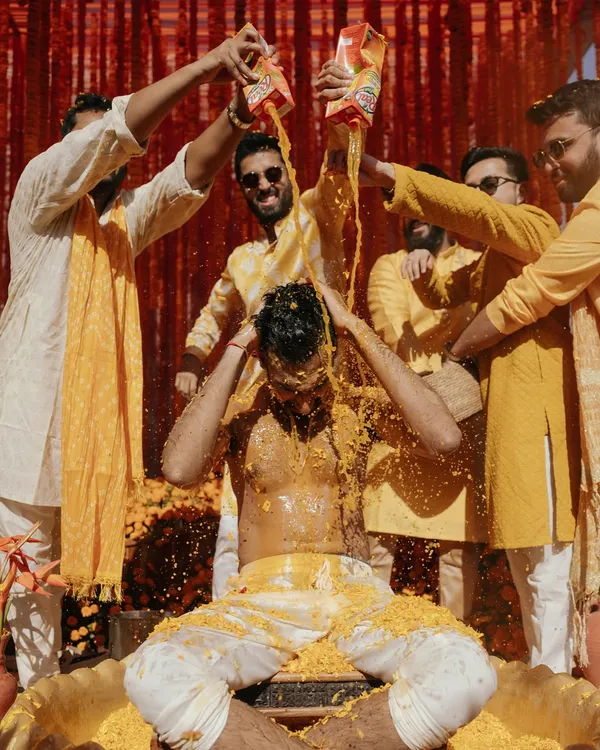 The groom's Haldi ceremony, a moment of pure, unadulterated fun and tradition. The splash of juice adds a dynamic and memorable element to the photograph.