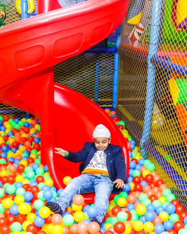 A vibrant shot of our massive red spiral slide, where kids can zip down into a sea of colorful balls. This is one of the main attractions in our multi-level soft play area, promising endless fun.
