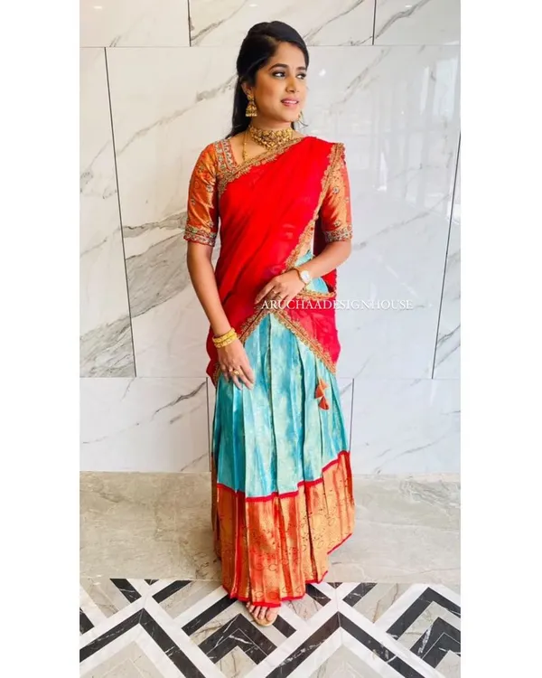 A full view of a gorgeous half saree, or langa voni, created from an old saree. The client wanted a bright, festive look, so we paired a vibrant red dupatta and blouse with a contrasting turquoise pleated skirt, highlighting the original saree's gold border.