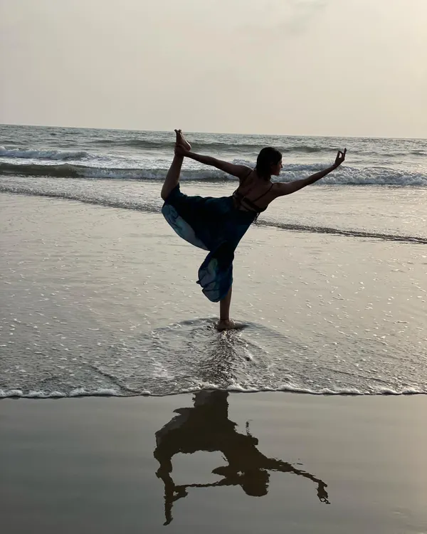 Performing the Natarajasana, or Dancer's Pose, as the waves recede. The reflection on the wet sand creates a beautiful symmetry, mirroring the balance we seek to create within ourselves.