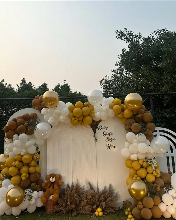A beautiful outdoor baby shower setup with a teddy bear theme. We used an arch of white, gold, and brown balloons, pampas grass, and a cute teddy bear to create a warm and inviting backdrop for the celebration.