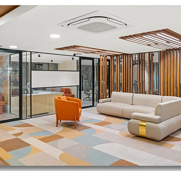 The waiting lounge at Unitus Capital in Bangalore, featuring a colorful geometric rug and modern furniture. The use of glass walls and wooden slats creates a space that is both open and structured.