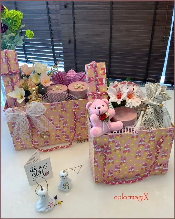 A pair of our signature 'Pretty in Pink' hampers for a baby girl. These gift totes are filled with floral arrangements, a pink teddy bear, and other beautifully wrapped items, complete with an 'It's a girl' announcement card.