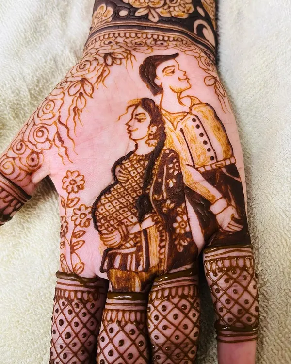 A detailed close up of a maternity couple portrait on the palm. I focus on capturing the likeness and the loving bond between the parents to be, making it a central part of the baby shower mehendi design.