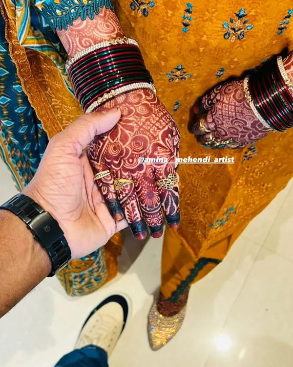 A beautiful moment captured between the couple, with the bride's rich henna stain and bangles on full display.