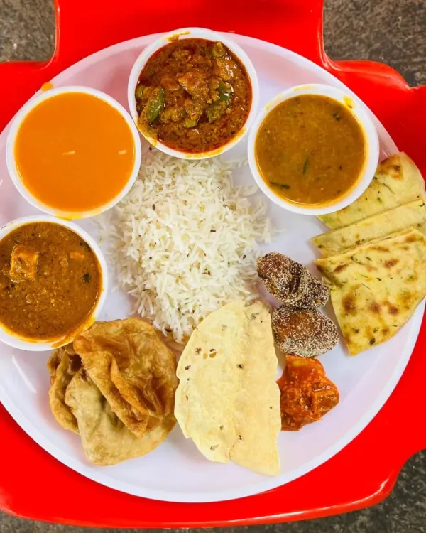 A complete wedding thali we served at an event in Pen, Maharashtra. It includes paneer and vegetable curries, dal, rice, hot puri, naan, and sweets.