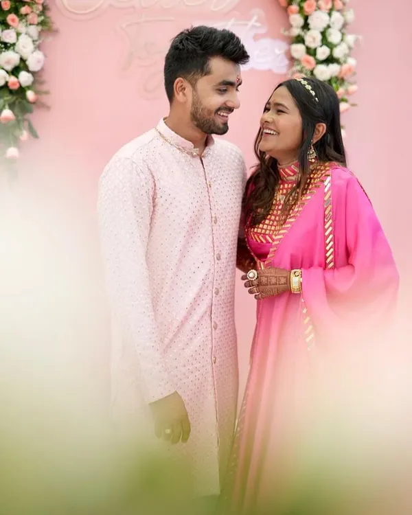 A beautiful, candid moment between a couple dressed in coordinated pink ethnic wear. The bride-to-be is wearing my hot pink Rajputani-style outfit.