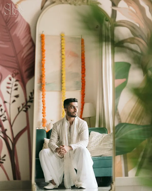 A quiet moment of reflection for the groom, Kapil, before his engagement. The mirror shot adds a creative layer, and the soft lighting creates a calm, artistic mood.