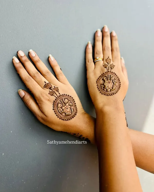 A beautiful and modern take on mehendi. This design features a circular, jewelry-like pattern on the back of the hand, connected to a matching design on the middle finger.